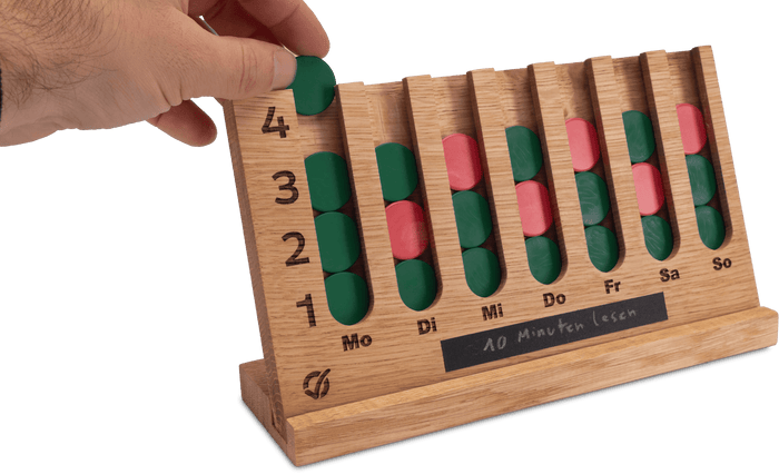 Hand legt grünen Chip in Habit Tracker aus Eichenholz – GoalBalance Gewohnheitstracker